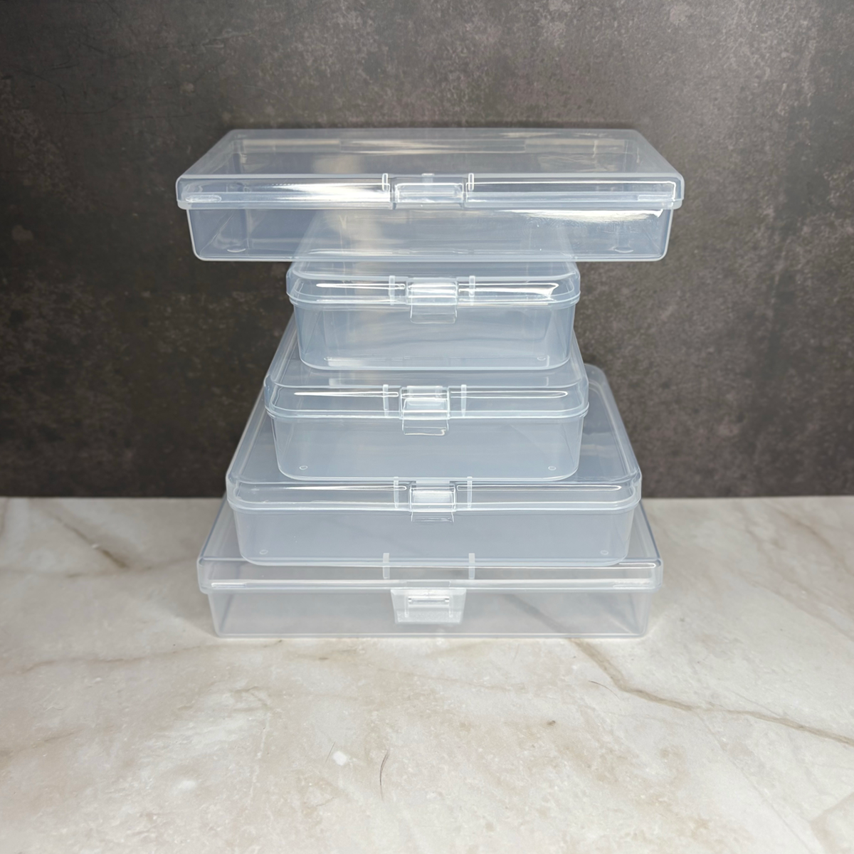 Stack of clear plastic storage containers on a marble surface with a dark background
