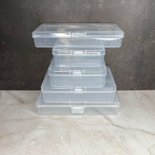 Stack of clear plastic storage containers on a marble surface with a dark background